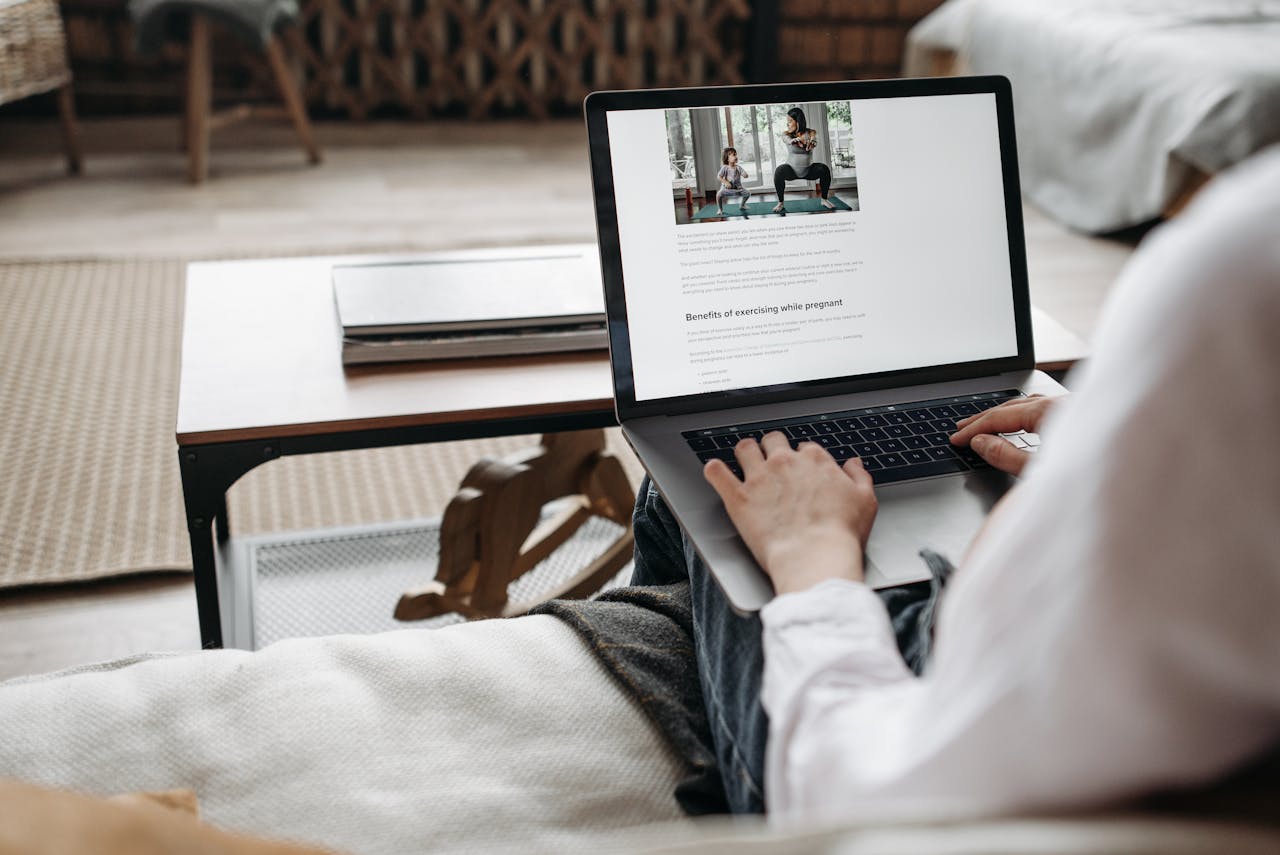 Person working remotely on a laptop in a cozy home setting, emphasizing comfort and technology.